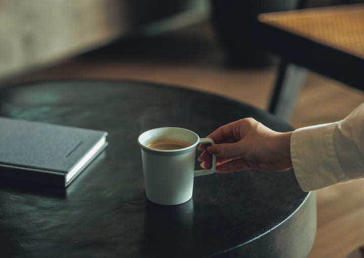 写真：コーヒーカップを手に取る女性